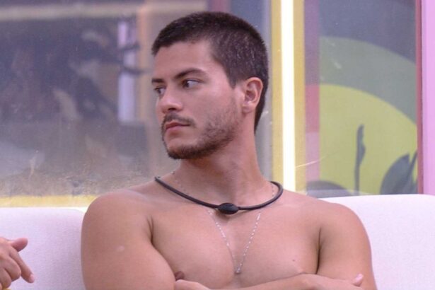 Arthur Aguiar sem camisa, olhando para o lado, sentado na varanda do BBB 22