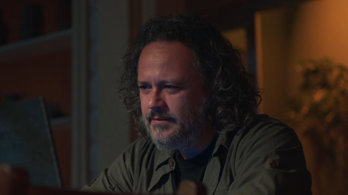 Danton Mello caracterizado como Mateus em cena da novela Um Lugar ao Sol. Ele está olhando sério para um notebook.