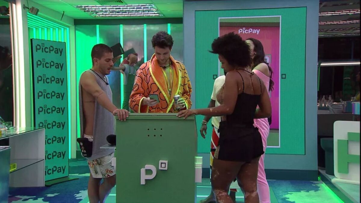 Lucas de roupão laranja ao lade de Arthur Aguiar de camisa regata e Natália, descobrem tema da festa do Líder.