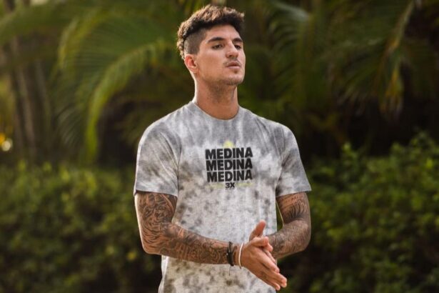 Gabriel Medina em uma foto na praia, utilizando uma camiseta branca estampada com sua marca