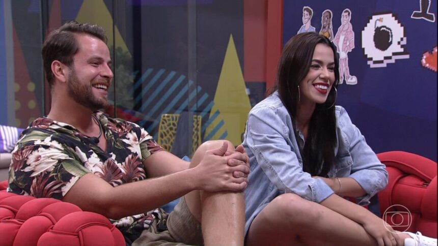 Gustavo e Larissa sentados no sofá da casa de vidro falando com Tadeu Shcmidt no BBB 22 deste domingo, 13/02/2022