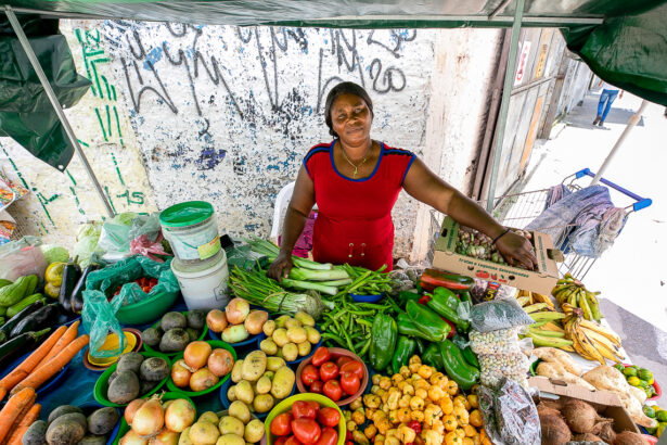 Haitiana em frente a banca de frutas