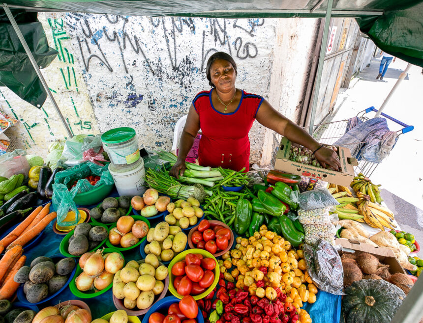 Haitiana em frente a banca de frutas