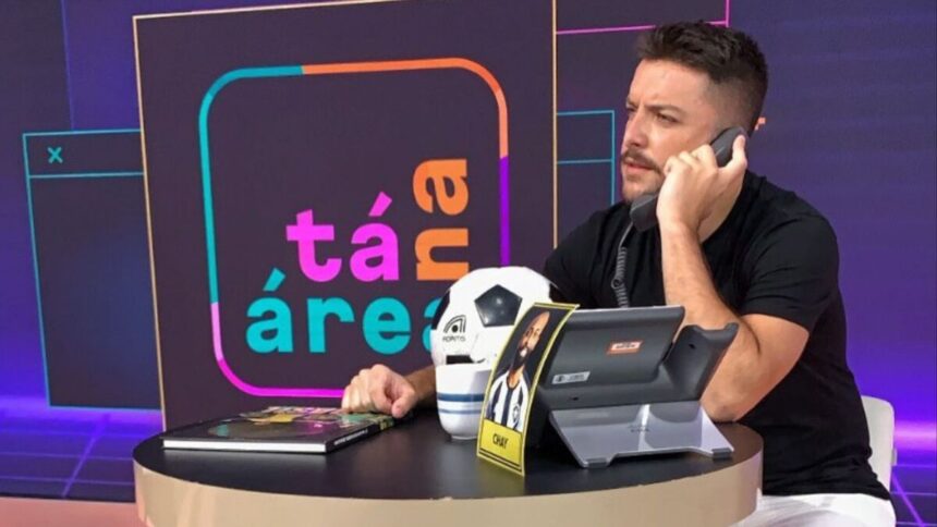 Igor Rodrigues falando no telefone em bastidores do programa Tá na Área, do SporTV