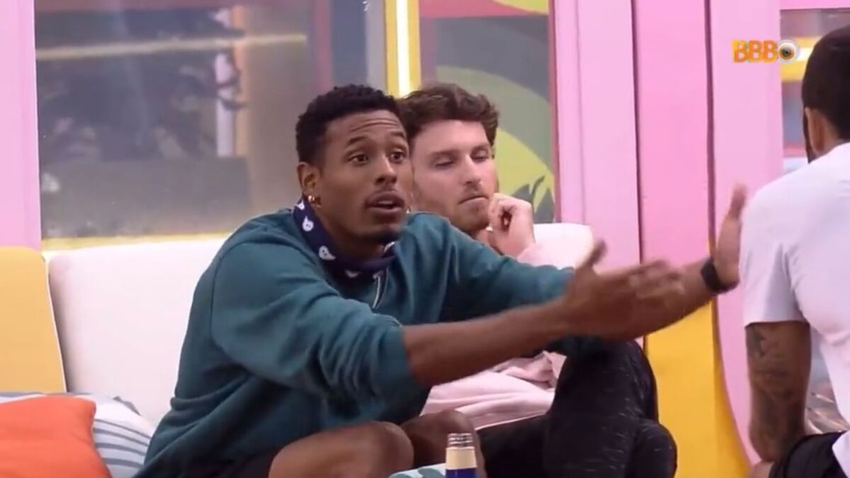 Paulo André sentado na área externa da casa ao lado de Lucas e Pedro Scooby conversando sobre o discurso de eliminação de Tadeu Schmidt no BBB 22