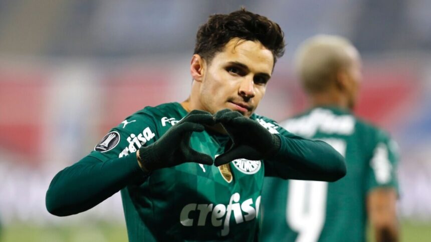 Jogador Raphael Veiga fazendo coração com as mãos e comemorando um gol com a camisa do Palmeiras