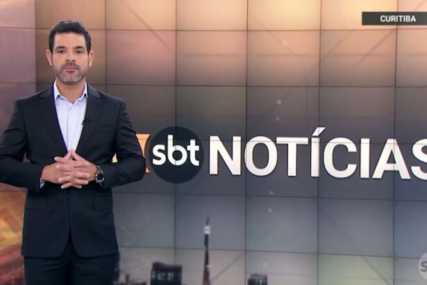 Darlisson Dutra nos estúdios do SBT Notícias, em frente ao telão do noticiário