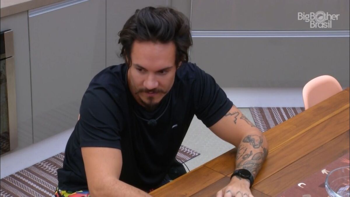 Eliezer de camisa preta sentado na cozinha do BBB 22.