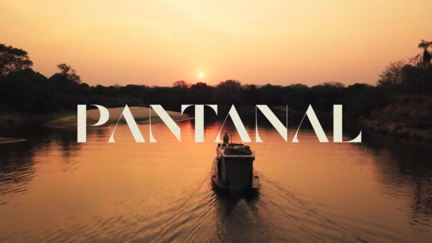 Logo da novela Pantanal por traz de um rio com um barco no meio