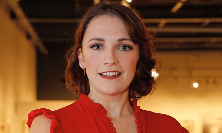 Charlotte Ritchie, de vestido vermelho, sorri