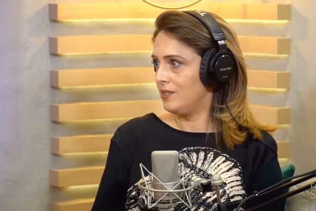 Cristiane Cardoso em trecho de sua entrevista para o podcast Fora de Série - ela usa fones nos ouvidos e um microfone de rádio perto da sua boca