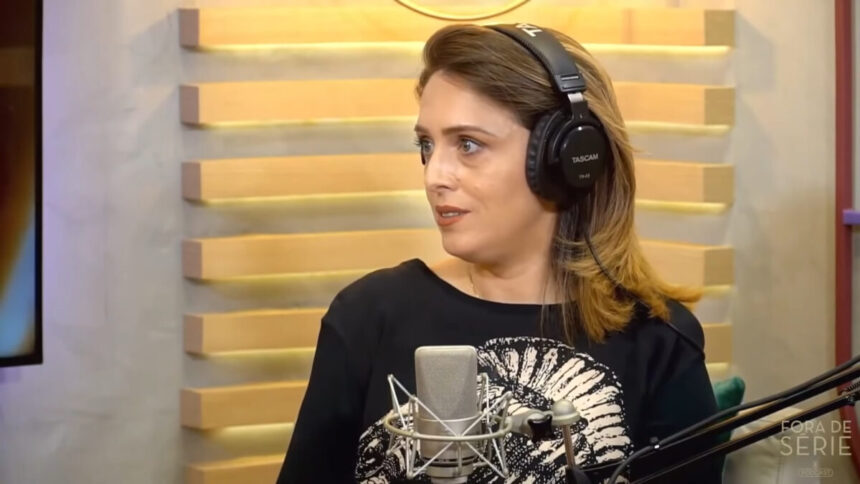 Cristiane Cardoso em trecho de sua entrevista para o podcast Fora de Série - ela usa fones nos ouvidos e um microfone de rádio perto da sua boca