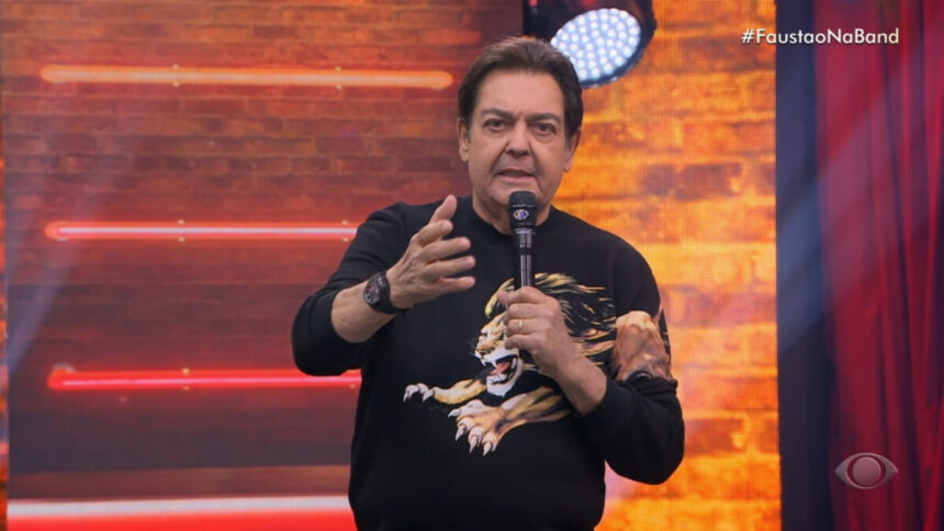 Fausto Silva no palco do seu programa na Band, apresentador veste uma blusa preta