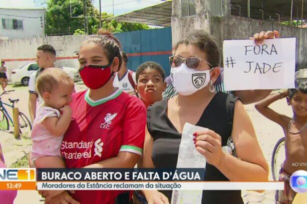 Mulher com uma criança no colo e uma outra do lado segurando um papel e atrás dela um jovem com uma placa de Fora Jade.