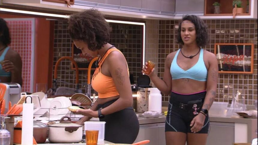 Linn de top azul próxima de Jessilane na cozinha da xepa do BBB 22.