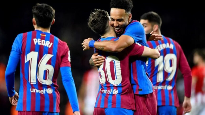 Jogadores em campo e comemorando um gol com a camisa do Barcelona