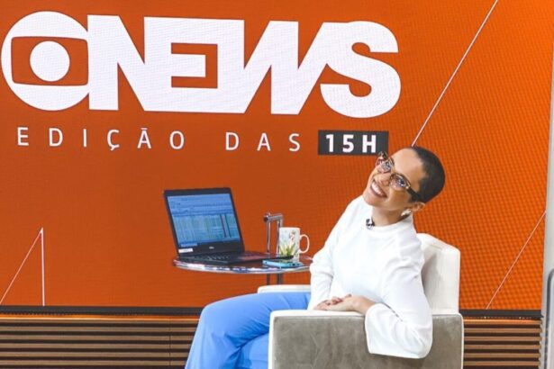 Lilian Ribeiro nos estúdios da GloboNews, sentada em uma poltrona em frente ao telão