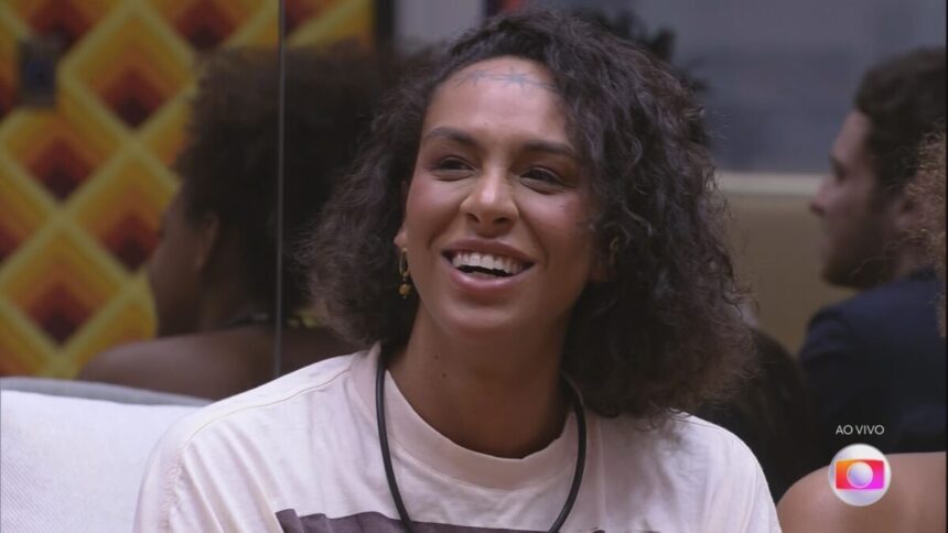 Linn da Quebrada sorrindo no sofá da sala do BBB 22