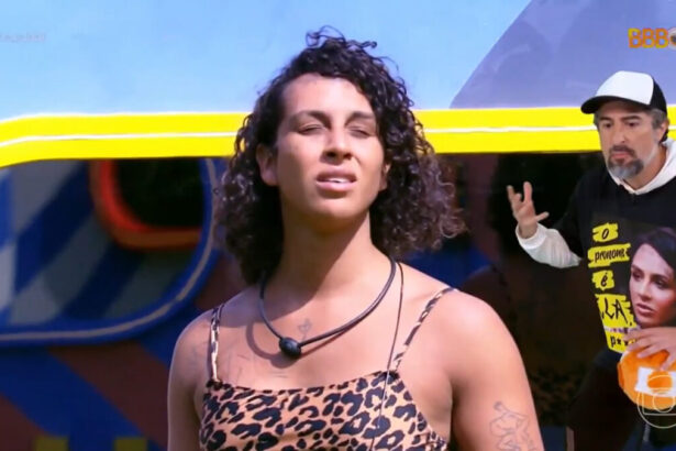 Linn da Quebra ao fundo, com Marcos Mion à frente e vestindo uma blusa militando sobre as falas de transfobia no BBB 22