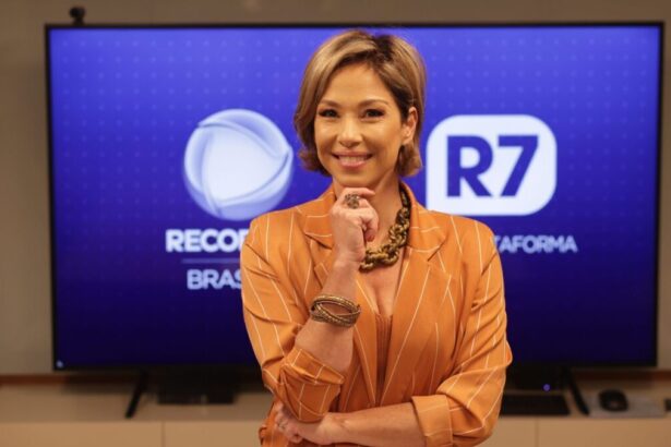 Neila Medeiros em foto posada, em frente a um telão com os logos da Record TV e R7