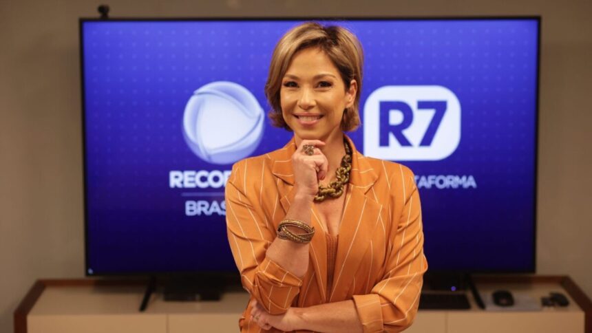 Neila Medeiros em foto posada, em frente a um telão com os logos da Record TV e R7