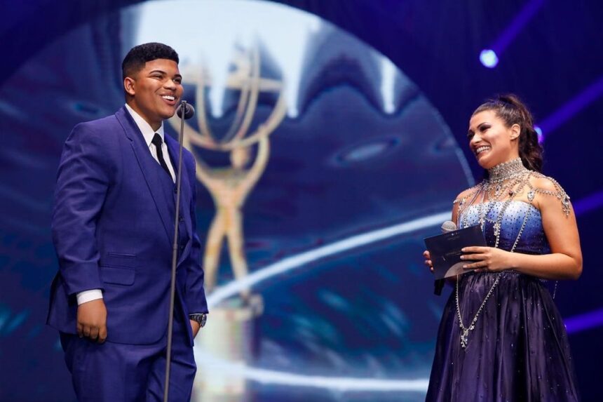 Paulo Neto, de terno azul, recebendo o prêmio no palco do evento