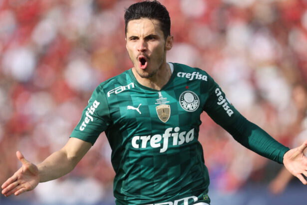 Raphael Veiga comemorando um gol com a camisa do Palmeiras, de braços abertos