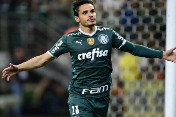 Raphael Veiga, de braços abertos, comemorando um gol com a camisa do Palmeiras