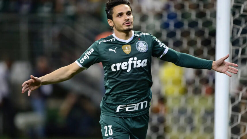 Raphael Veiga, de braços abertos, comemorando um gol com a camisa do Palmeiras