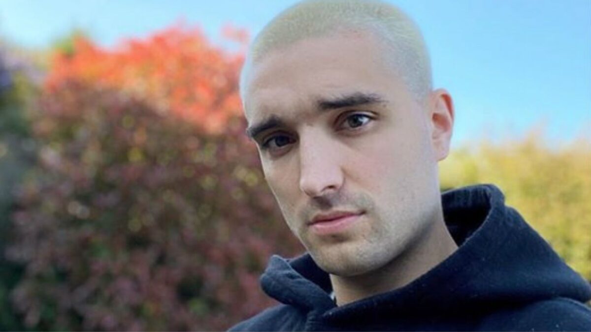 Tom Parker olha sério para a câmera