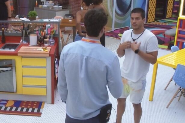 Lucas de frente a Arthur Aguiar na cozinha do BBB 22. Os dois estão discutindo