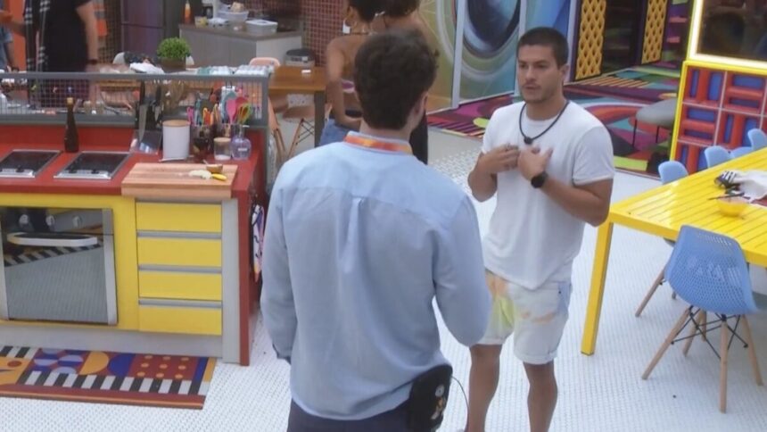 Lucas de frente a Arthur Aguiar na cozinha do BBB 22. Os dois estão discutindo