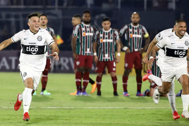 Jogadores do Olimpia, à frente da imagem, comemorando a vitória contra o Fluminense, que tem seus jogadores ao fundo