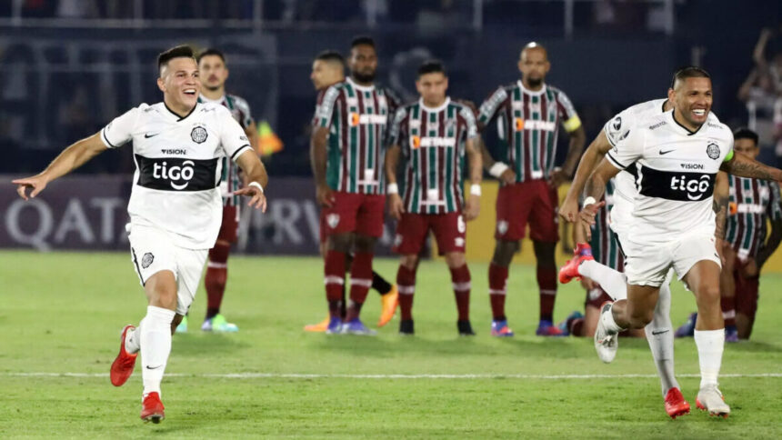 Jogadores do Olimpia, à frente da imagem, comemorando a vitória contra o Fluminense, que tem seus jogadores ao fundo