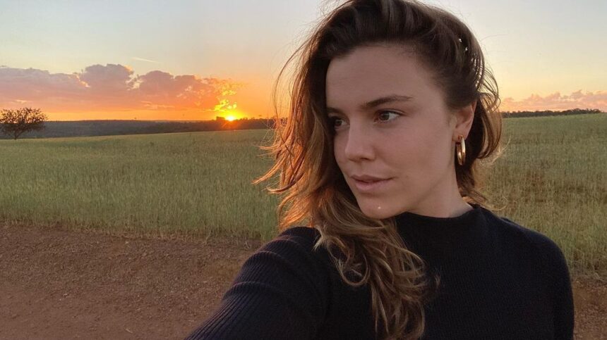 Alice Wegmann em foto posada com um pôr do sul ao fundo