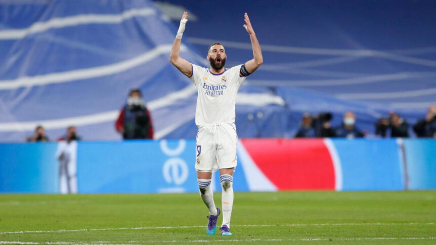 Benzema exaltado com os braços abertos em campo com a camisa do Real Madrid