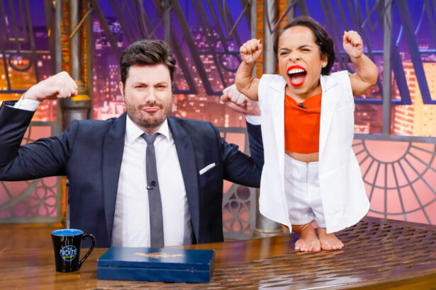 Danilo Gentili fazendo u moque com os braços no estúdio do The Noite, com Camila Feitosa fazendo o mesmo movimento em cima da bancada