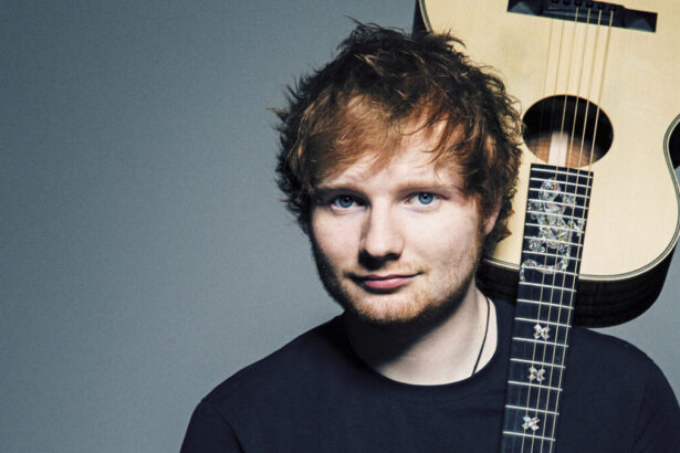 Ed Sheeran em uma foto posada, com um violão nas costas