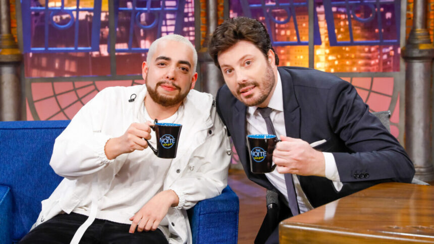 Lucas Selfie e Danilo Gentili lado a lado nos estúdios do The Noite. Ambos com uma caneca tendo o logo do programa nas mãos