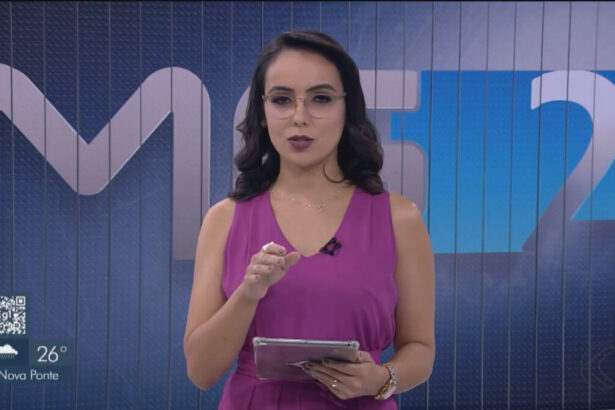 Muriele Silva com um vestido rosa, segurando um tablet em trecho do MG2 de Uberlândia