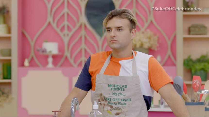 Nicholas Torres em trecho do Bake Off Celebridade. Ele azul um avental na tenda do reality