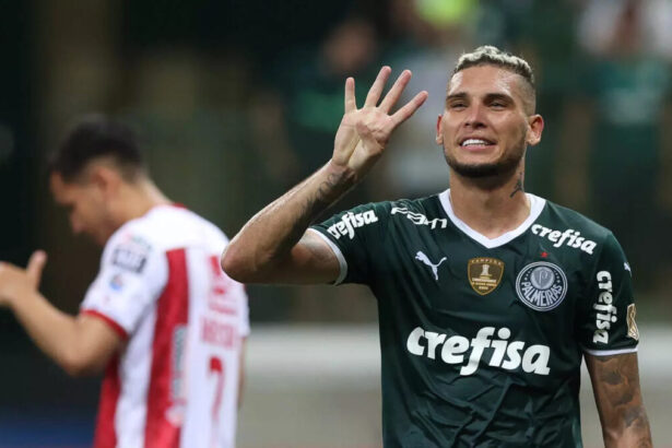 Jogador Rafael Navarro em campo com a camisa do Palmeiras e fazendo o sinal de quatro com os dedos da mão