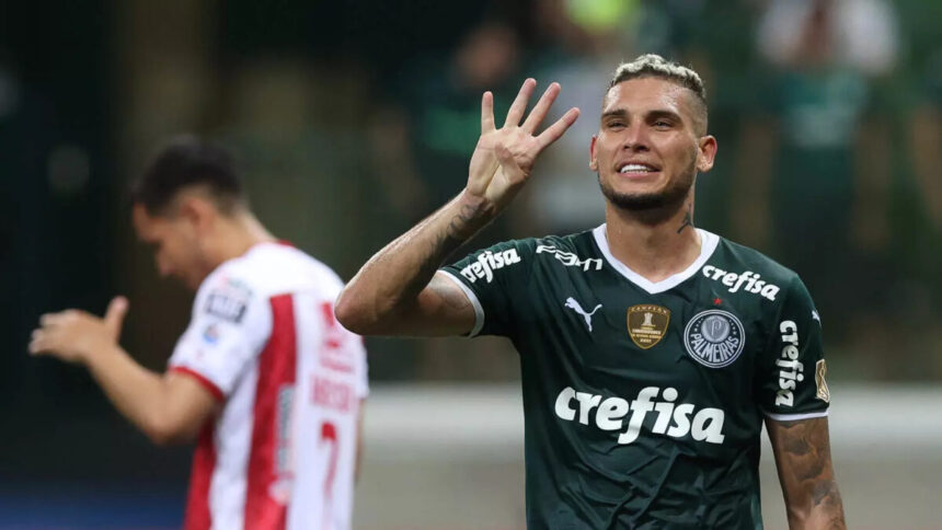 Jogador Rafael Navarro em campo com a camisa do Palmeiras e fazendo o sinal de quatro com os dedos da mão