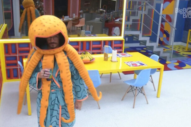 Eliezer vestido de Monstro polvo, tomando água na cozinha do BBB 22