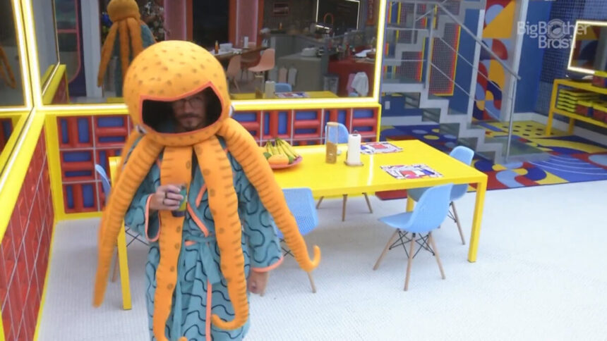 Eliezer vestido de Monstro polvo, tomando água na cozinha do BBB 22