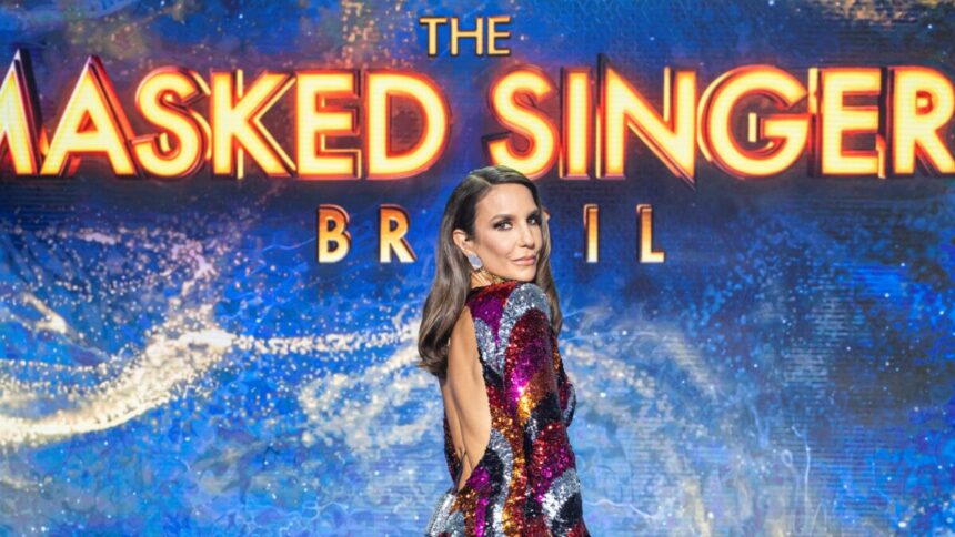 Ivete Sangalo em frente ao logo do The Masked Singer Brasil