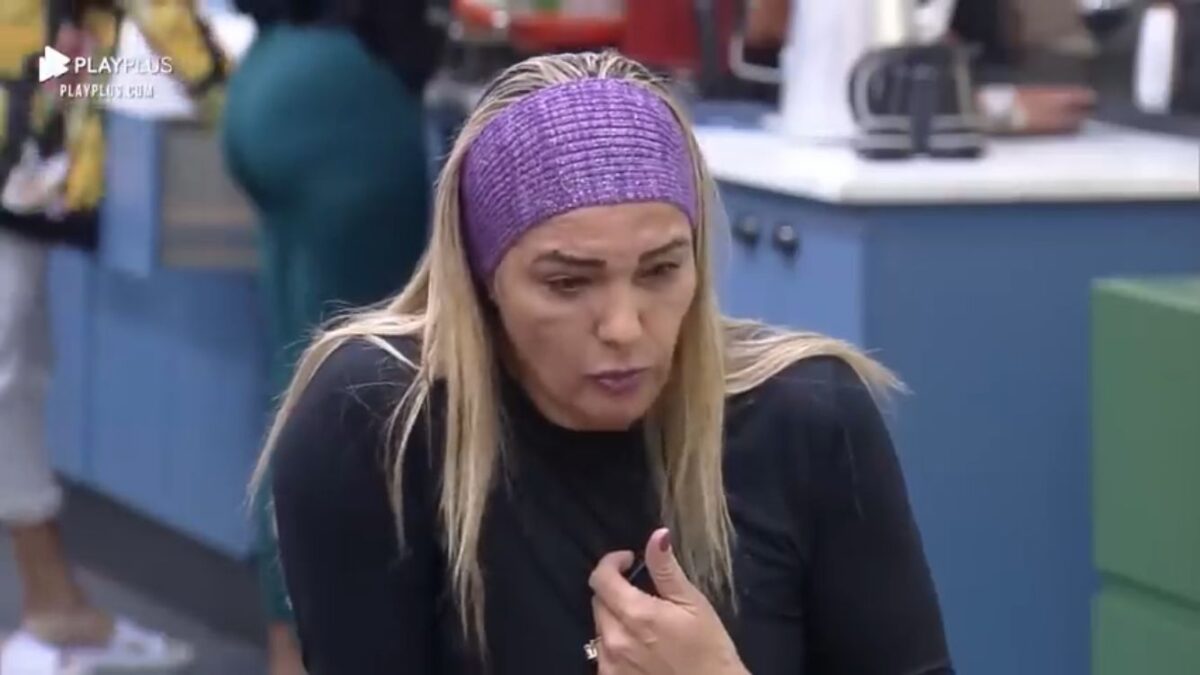 Andreia com um pano roxo na cabeça com semblante sério.