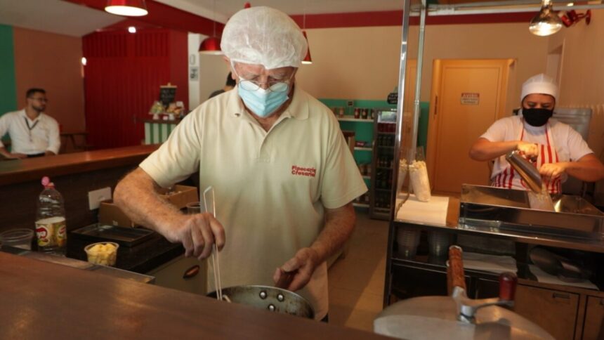 Homem trabalhando em uma cozinha de restaurante, em trecho do Arquivo A sobre emprego depois dos 50 anos