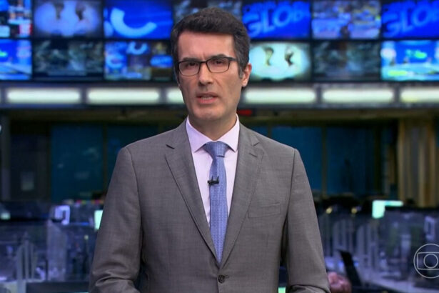 Fabio Turci em pé nos estúdios do Jornal da Globo, com a redação de jornalismo ao vivo