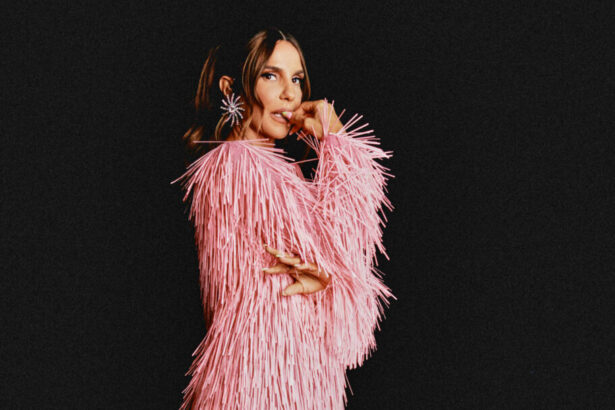 Ivete Sangalo em foto posada com uma roupa rosa em um fundo preto